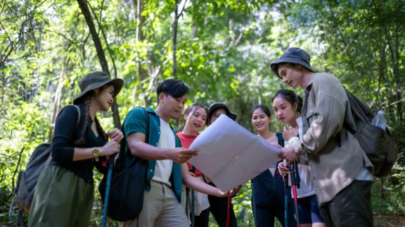 Global denken, lokal handeln: Barcamp zu Klimabildung und nachhaltigem Lernen Sechs Jugendliche sind auf einer Exkursion im Wald. Sie halten und betrachten zusammen einen Plan.