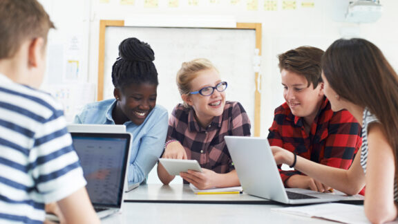 Group Of Teenage Students Collaborating On Project In IT Class